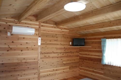 Pokój z drewnianą ścianą i telewizorem w obiekcie Tokai Beach Outdoor Campsite Mori no Shonen Oji - Vacation STAY 42348v w mieście Noma