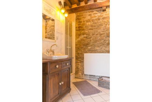 ein Badezimmer mit einem Waschbecken und einem Waschtisch mit einem Spiegel in der Unterkunft Les Trois Faisans in Bligny-sur-Ouche