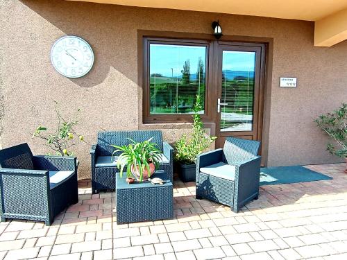 eine Gruppe von Stühlen und eine Uhr an der Seite eines Gebäudes in der Unterkunft Apartma Xanadu in Slovenske Konjice