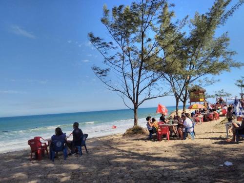 a group of people sitting at tables on a beach at Espaço familiar in Maricá