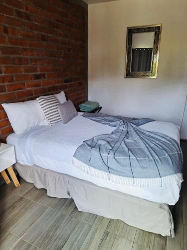 a bed in a room with a brick wall at Rancho Matalote en Valle de Guadalupe in Valle de Guadalupe