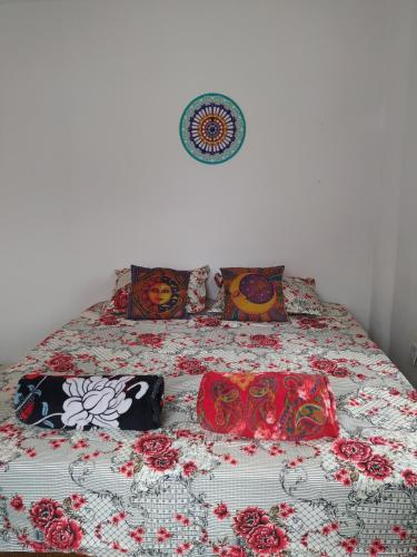 a bed with a floral bedspread and pillows on it at Hostel do Capao in Palmeiras