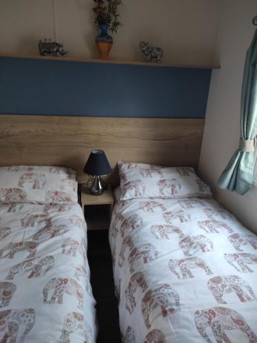 sypialnia z 2 łóżkami i lampką obok w obiekcie Torbay Holiday Home at The Waterside Holiday Park - With Deck and Sea View w mieście Torquay