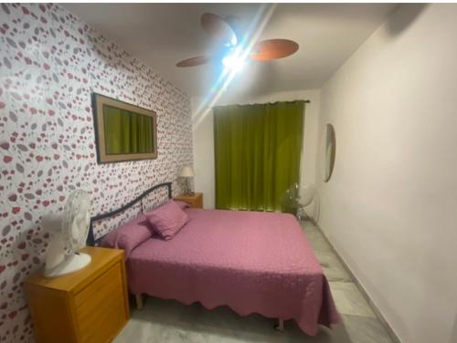 ein Schlafzimmer mit einem rosa Bett und einem grünen Vorhang in der Unterkunft Apartamento El Mirador in Aguadulce