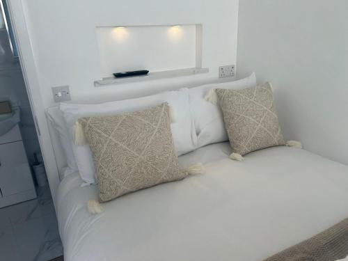 a white bed with two pillows and a mirror at The Little Nest @ Slaney House in Lahinch