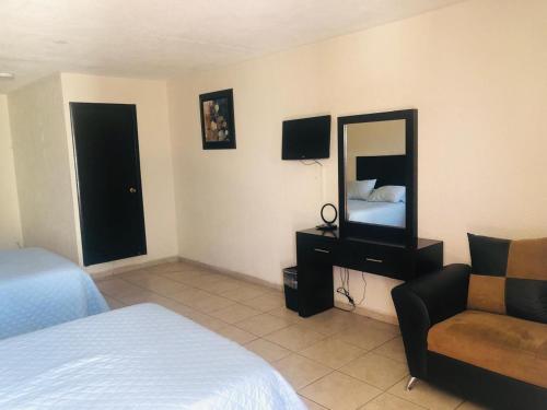 um quarto com uma cama, um espelho e uma cadeira em Hotel nuevo atardecer em Cabo San Lucas