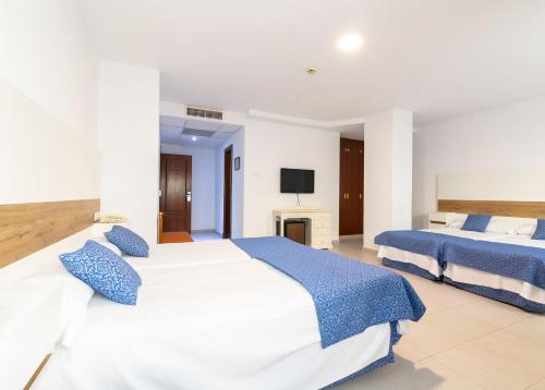 a bedroom with two beds and a tv at Hotel Pozo del Duque II in Zahara de los Atunes