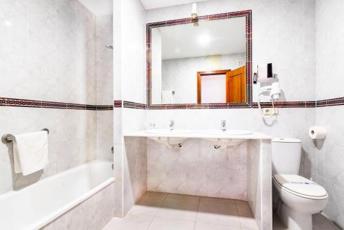 a bathroom with a sink and a toilet and a mirror at Hotel Pozo del Duque II in Zahara de los Atunes