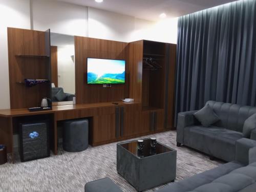 uma sala de estar com um sofá e uma televisão de ecrã plano em فندق انسام طيبة للضيافة em Al Madinah