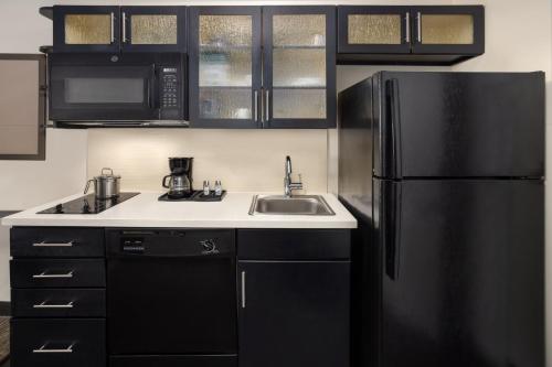 a kitchen with a black refrigerator and a sink at Candlewood Suites Philadelphia - Airport Area by IHG in Chester