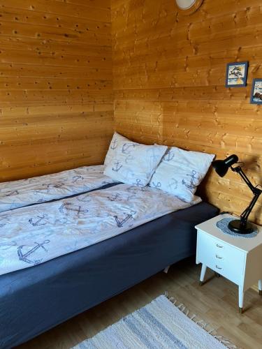 a bed in a room with a lamp on a table at Naustplassen Rorbuer in Ballstad