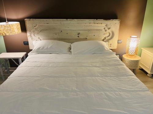 コンヴェルサーノにあるJENNY HOUSEの白いヘッドボードとランプ付きの大きな白いベッド