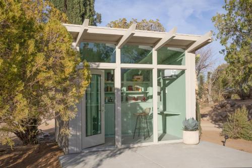 a small green house with a pergola at The Bungalows by Homestead Modern in Joshua Tree