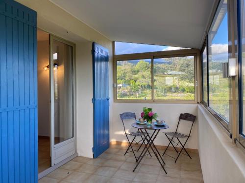 einen Balkon mit einem Tisch, 2 Stühlen und einem Fenster in der Unterkunft La maison des cerisiers in Bédoin