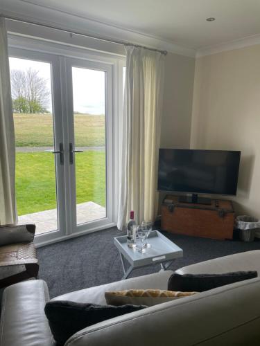 a living room with a couch and a large window at Highthel Holiday Home by the Northumberland Coast in Morpeth