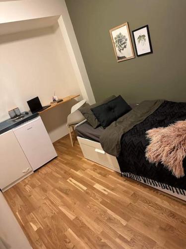 a small bedroom with a bed and a wooden floor at Hybel nær flyplass og kort vei til sentrum in Tromsø