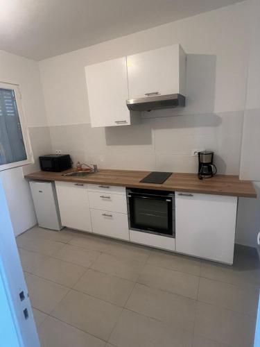une cuisine avec des armoires blanches et un comptoir en bois dans l'établissement T2 Colombes proche toutes commodités #4, à Colombes