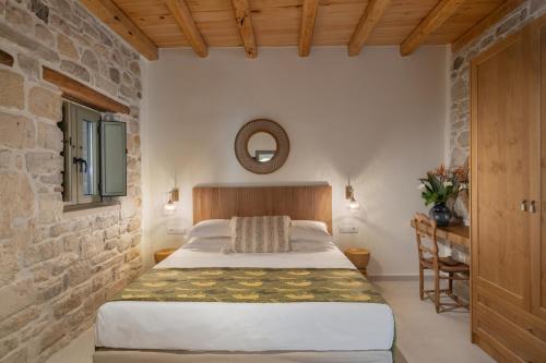 a bedroom with a bed and a stone wall at St-Ten Stone Built Village in Áyioi Dhéka