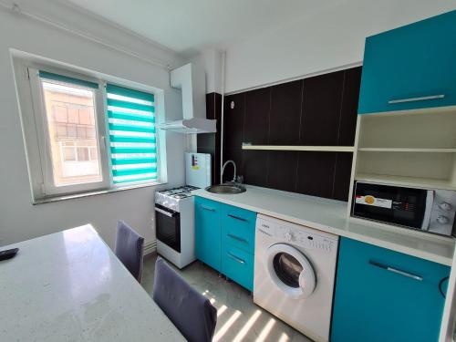 eine Küche mit blauen Schränken und einer Waschmaschine in der Unterkunft Romanescu One Apartament in Craiova