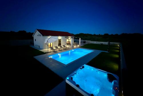 a swimming pool in front of a house at night at Villa Gemini in Zadar