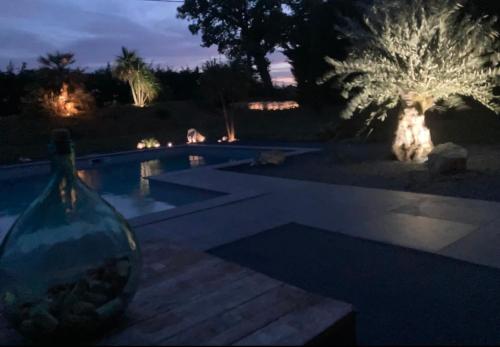 Castillon-SavèsにあるVilla avec piscineの前景に花瓶が置かれた夜のプール