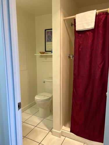 a bathroom with a toilet and a red shower curtain at Port Townsend Inn in Port Townsend