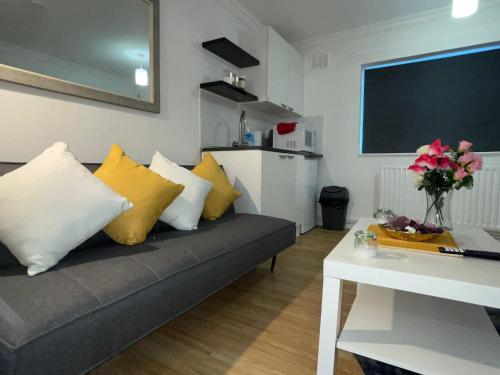 uma sala de estar com um sofá com almofadas amarelas e brancas em Stevenage Studios - Superior Suite em Stevenage