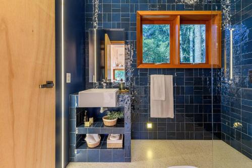 a blue tiled bathroom with a sink and a mirror at Casa Árbol - Pousada Nacarapina in São Francisco de Paula