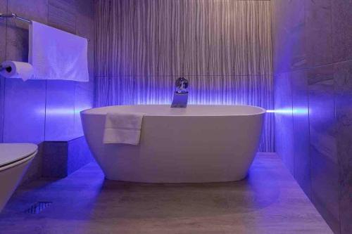 a white bath tub in a bathroom with purple lights at 522 The Granger in Cape Town