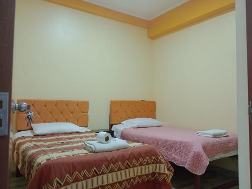 dos camas sentadas una al lado de la otra en una habitación en Hostal El Conde, en Tacna