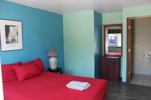 a bedroom with a red bed and blue walls at Seaside International Hostel in Seaside