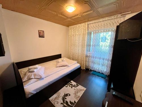 Habitación pequeña con cama y ventana en Casa Munții Rodnei, en Borşa