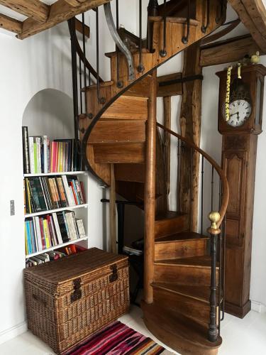 un escalier en colimaçon avec une horloge à côté d'une étagère à livres dans l'établissement Deux chambres en plein cœur de Montmartre, Paris, à Paris