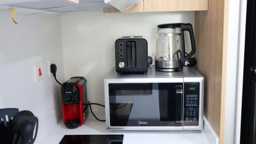 a microwave with a coffee maker on top of it at Jupiter 1BR Apartment - Contemporary Living in Oasis, Near Louvre Abu Dhabi in Abu Dhabi