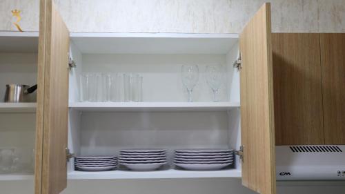 a cupboard filled with glasses and plates in a kitchen at Jupiter 1BR Apartment - Contemporary Living in Oasis, Near Louvre Abu Dhabi in Abu Dhabi