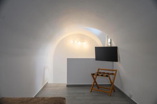 a room with a chair and a tv on a wall at Aegean Diamonds Luxury Suites in Monolithos