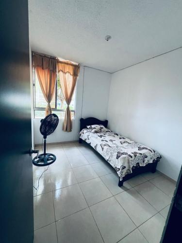 een slaapkamer met een bed, een stoel en een raam bij ESTANCIA MINIMA 3 NOCHES APARTAMENTO 3 HABITACIONES - 5 PERSONAS no aire acondicionado in Valledupar