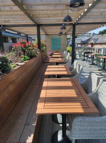 a row of wooden tables on a patio at Torbay Holiday Home at The Waterside Holiday Park - With Deck and Sea View in Torquay