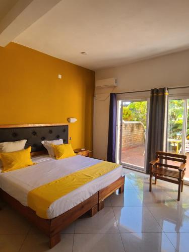 een slaapkamer met een groot bed met gele muren bij Hotel Les Cygnes in Antananarivo