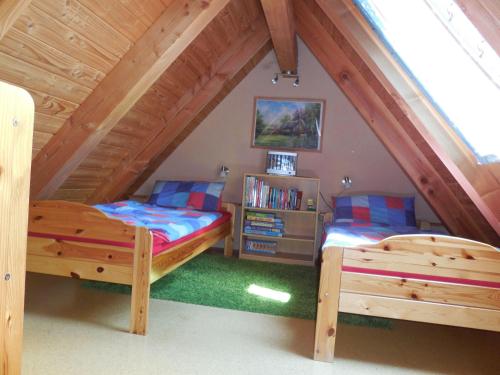 ein Schlafzimmer im Dachgeschoss mit 2 Betten und einem Bücherregal in der Unterkunft Ferienwohnung Kribitz Hodenhagen in Hodenhagen