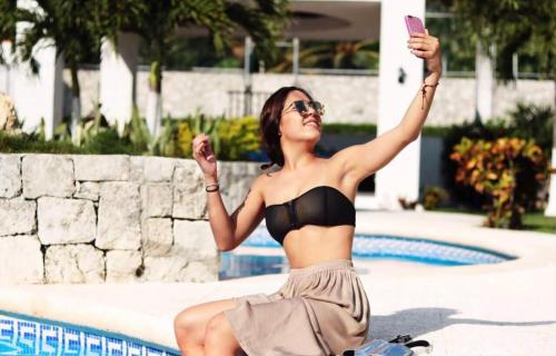 a woman in a bikini sitting next to a swimming pool at Amazing Villas at Las Cupulas in Cancún
