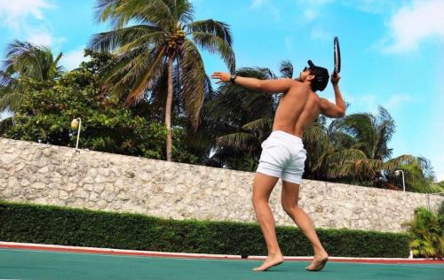 a man holding a tennis racket on a tennis court at Amazing Villas at Las Cupulas in Cancún