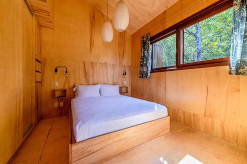 ein Schlafzimmer mit einem Bett in einem Holzzimmer in der Unterkunft Casa de Piedra - Pousada NaCarapina in São Francisco de Paula