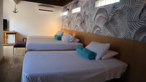 two beds in a room with white sheets and blue pillows at Hotel Rosario de Mar by Tequendama in Isla Grande