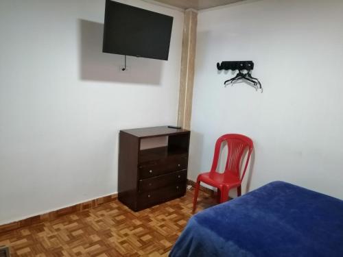 a bedroom with a bed and a tv and a chair at Hotel El Carretero in Popayan