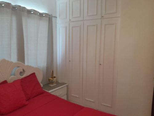 a bedroom with a red bed and a white closet at Se alquila apartamento amueblado en el centro de la ciudad in La Romana