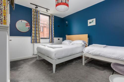 a bedroom with two beds and a blue wall at ART B&B in Blackpool