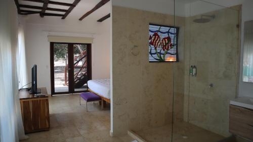 a bathroom with a glass shower with a bed and a television at Hotel Rosario de Mar by Tequendama in Isla Grande
