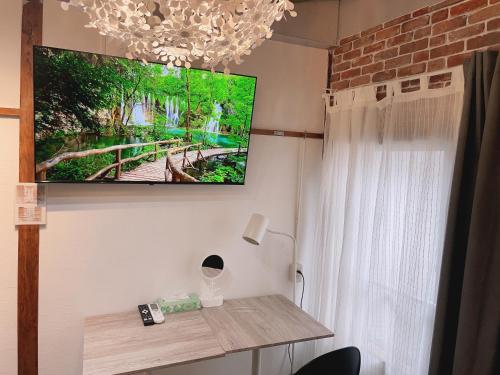 een flatscreen-tv aan een muur met een tafel bij Akira&chacha杉並区世田谷direct to shinjuku for 13 min 上北沢4分 近涉谷新宿 in Tokyo