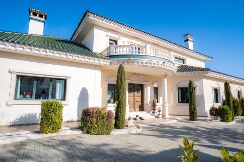 a large white house with a balcony at La Casa del Tejado Verde Toledo in Toledo